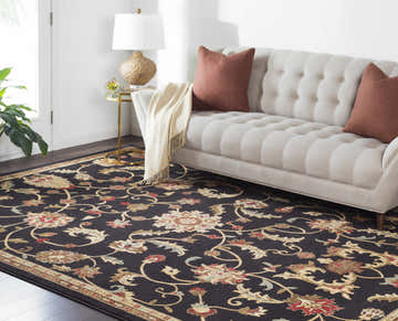 Living room scene with a Salona Luxe Black Rug, beige sofa, coral pillows, and gold accent table. Roomscene-Rectangle