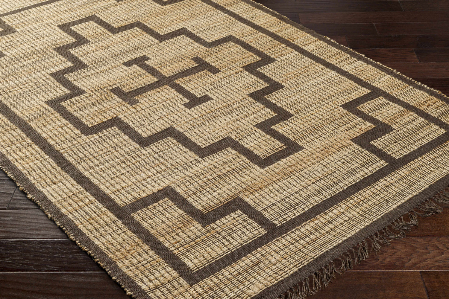 Close-up of the hand-woven Licha Jute Rug. Camel jute with eggplant geometric pattern and fringe detail. Farmhouse style. Corner