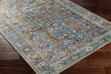 Close-up of the Kaif Washable Area Rug in teal, brown, and gold on dark wood floors. Traditional, farmhouse style rug. Corner