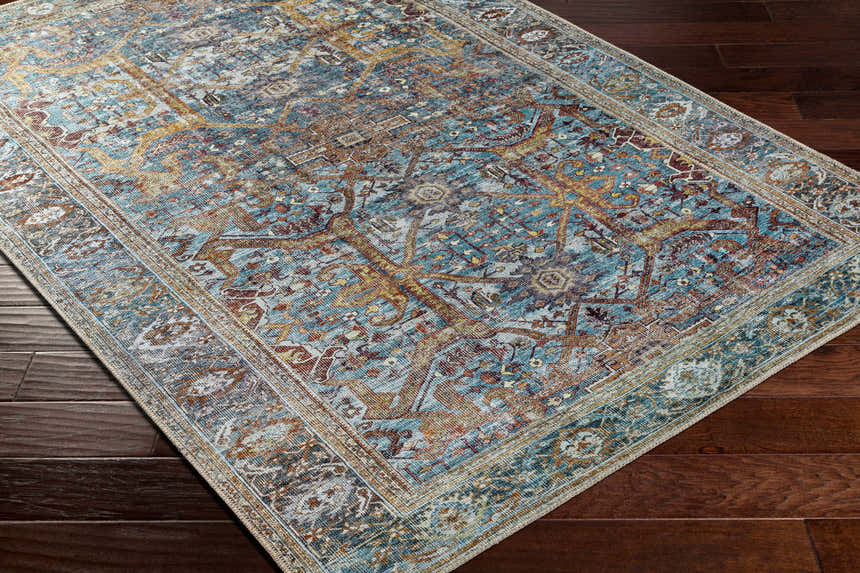 Close-up of the Kaif Washable Area Rug in teal, brown, and gold on dark wood floors. Traditional, farmhouse style rug. Corner