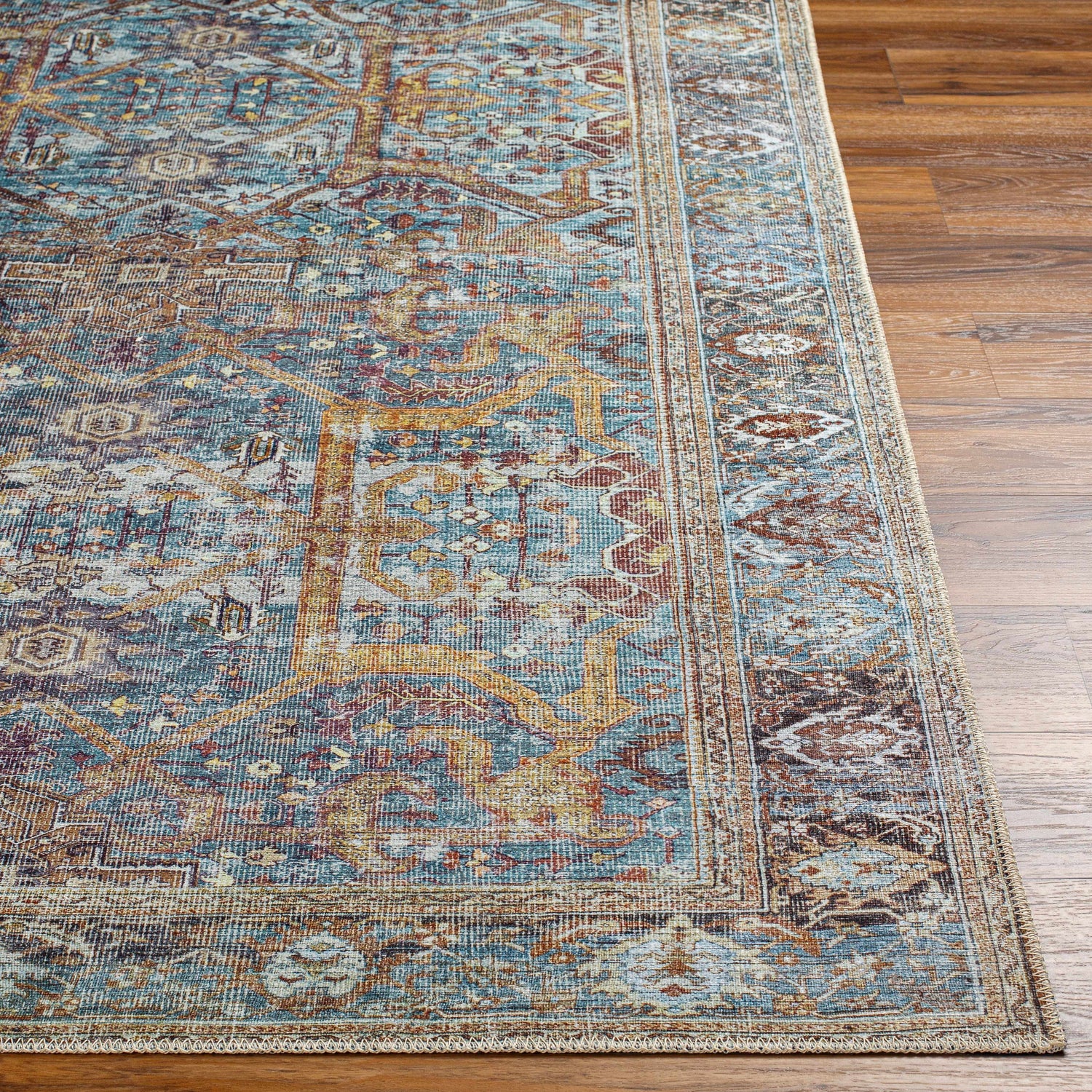 Close-up of the Kaif Washable Area Rug showing its traditional design, blue, brown, and gold colors, and machine-woven texture. Front