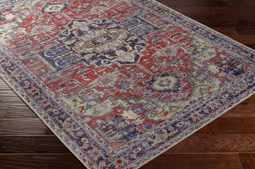 Close-up of Reza Red Washable Rug on dark wood floor. Features traditional, farmhouse style with garnet, bone, and cloud gray colors. Corner