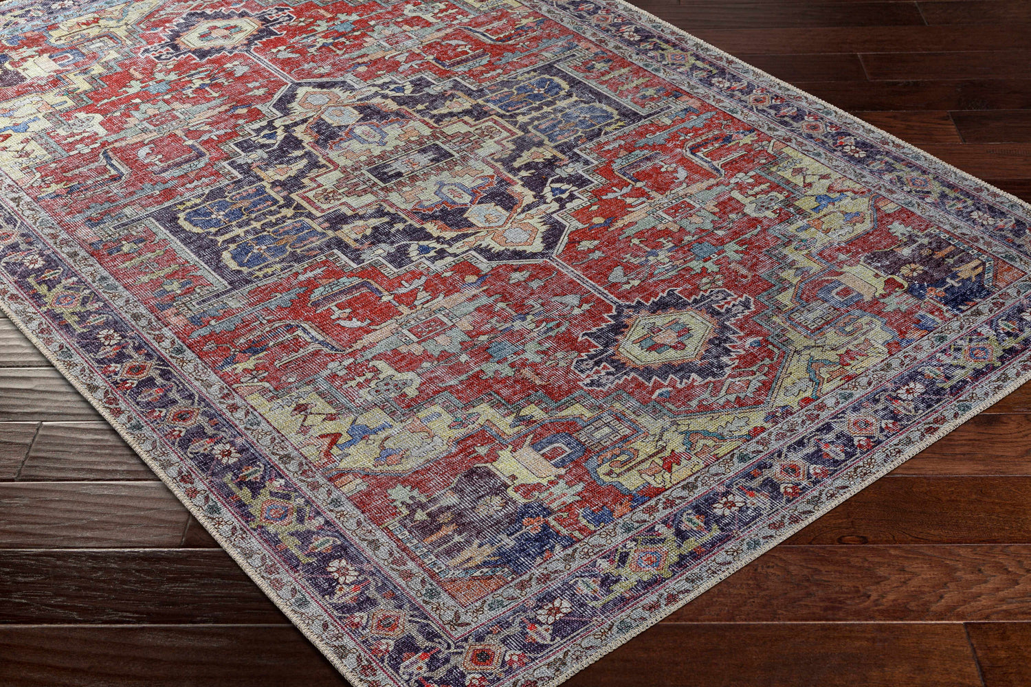 Close-up of Reza Red Washable Rug on dark wood floor. Features traditional, farmhouse style with garnet, bone, and cloud gray colors. Corner