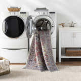 Laundry room scene with Reza Red Washable Rug being washed in a front load washing machine. Washing-Machine