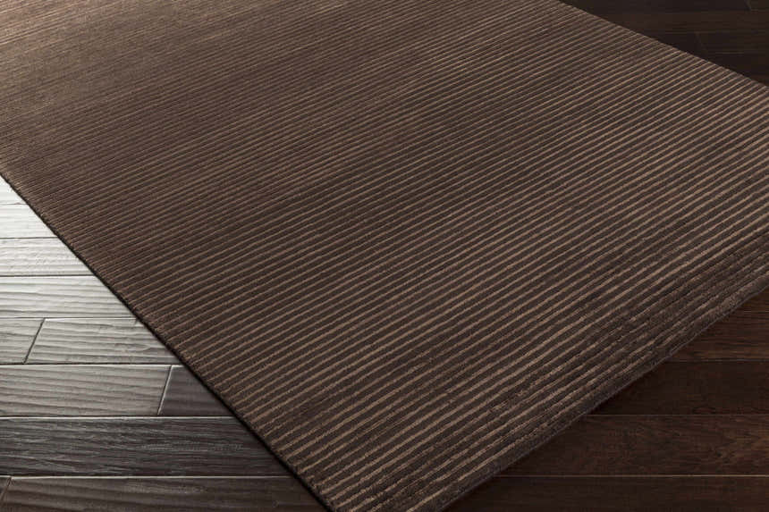 Close-up of the brown Sanatoga Area Rug showing its subtle striped pattern and hand-knotted texture. Corner