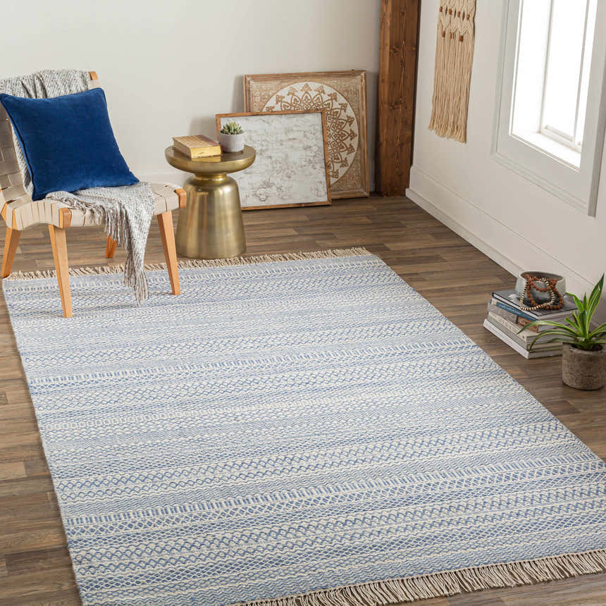 Living room scene with the blue and cream Sanc rug, chair with blue pillow, and gold side table. Roomscene-Rectangle