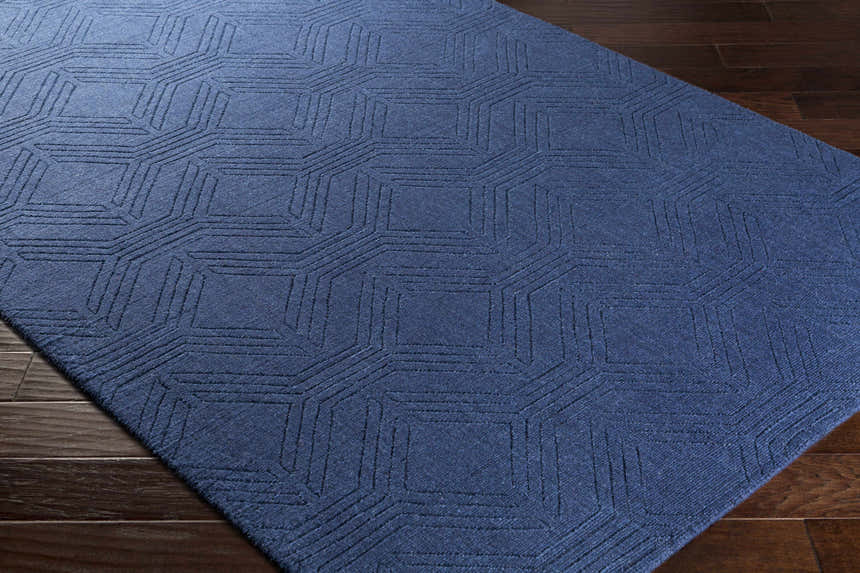 Close-up of the dark blue Sarona Area Rug, a hand-loomed wool rug with a geometric striped pattern. Corner