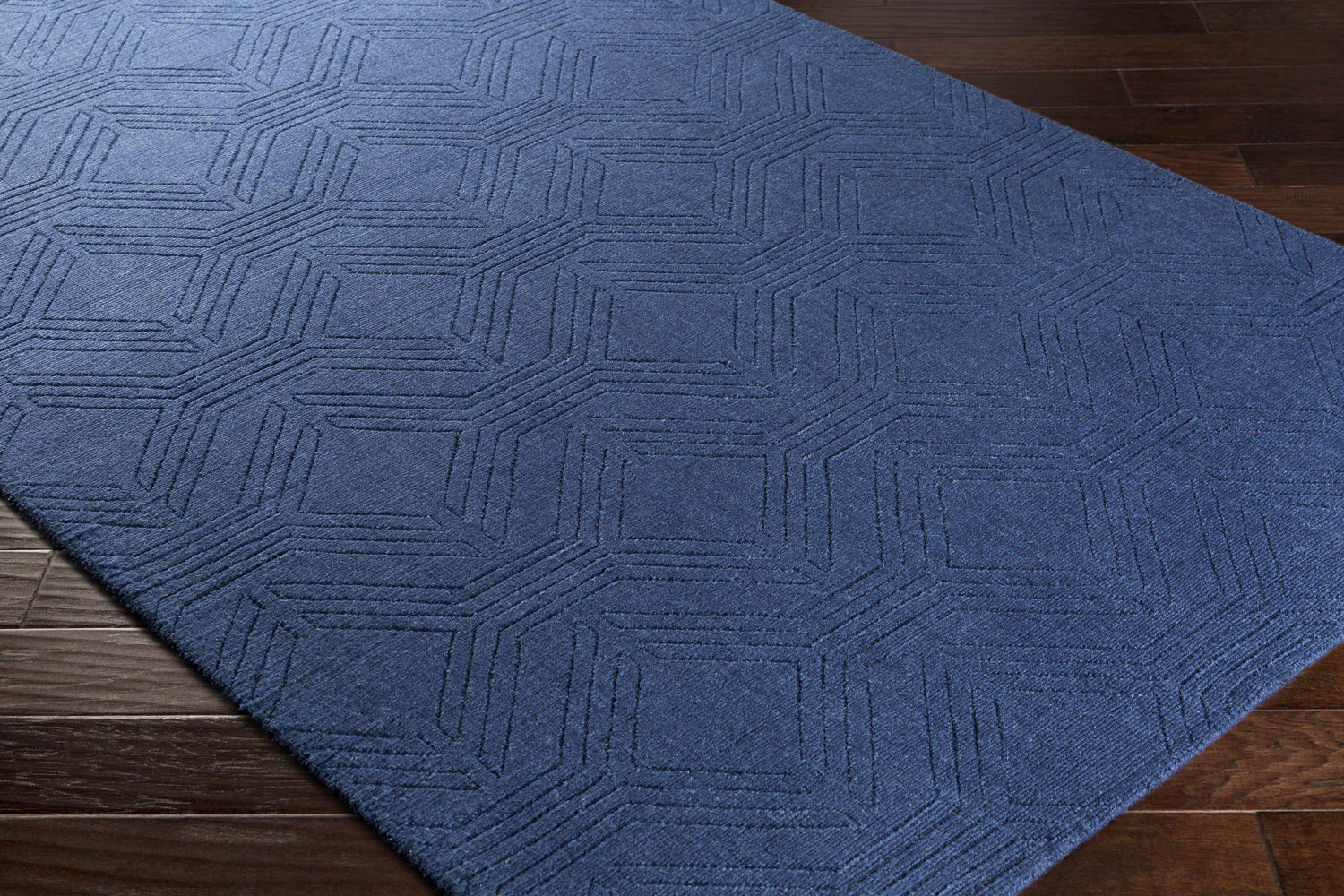 Close-up of the dark blue Sarona Area Rug, a hand-loomed wool rug with a geometric striped pattern. Corner
