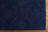 Close up of the dark blue, hand-loomed wool Sarona Area Rug with a raised geometric pattern. Corner