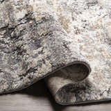 Close-up of the thick Satsop Rock Pattern Rug. Features black, charcoal, gray, ivory, and tan colors with a contemporary design. Fold