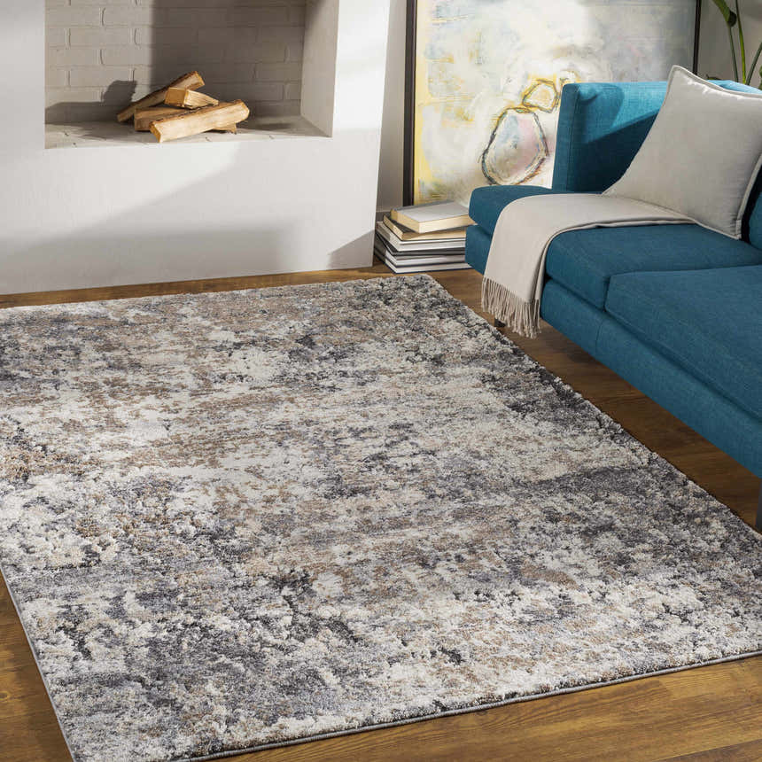 Living room scene with a Satsop Rock Pattern Rug in black, charcoal, gray, ivory, and tan beneath a blue sofa. Roomscene-Rectangle