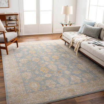 Living room with a light gray sofa and Saya Thick Luxe Statement Rug in light blue and gold. Roomscene-Rectangle