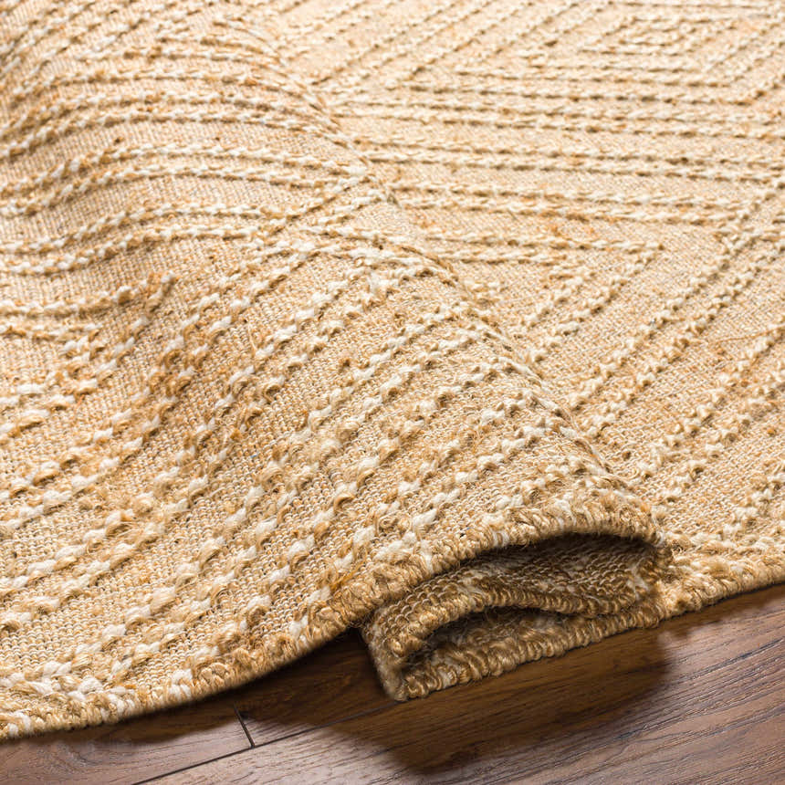 Close-up of the beige and ivory Dunne Area Rug, a hand-woven jute rug with a textured, striped pattern. Fold