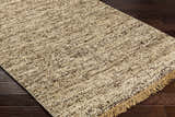 Close-up of the Tan Gopi Area Rug showing its jute and wool texture, tan and black colors, and fringed edge. Corner