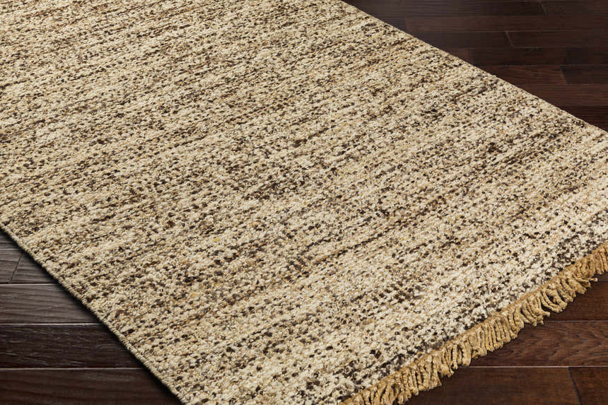 Close-up of the Tan Gopi Area Rug showing its jute and wool texture, tan and black colors, and fringed edge. Corner