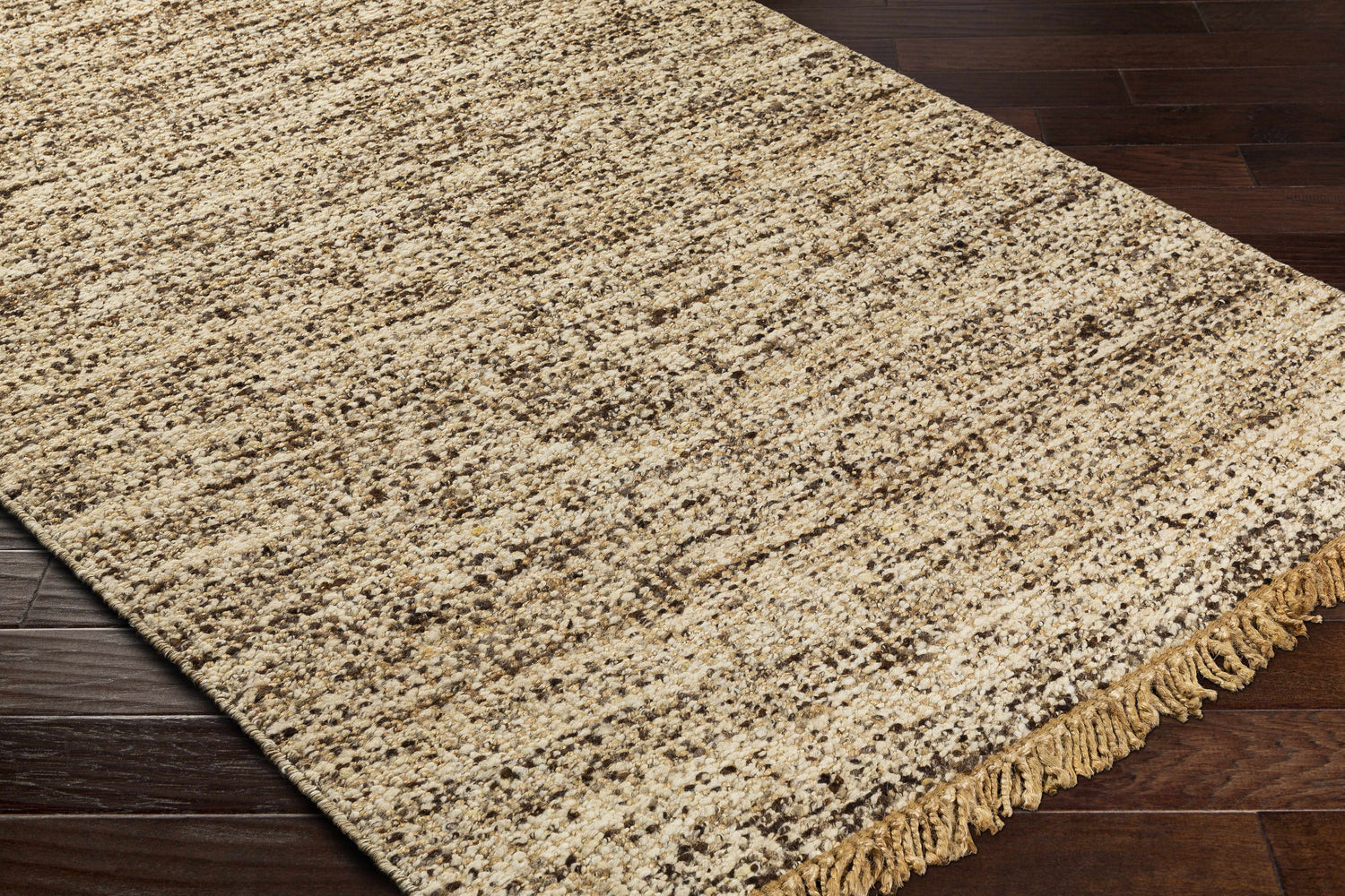 Close-up of the Tan Gopi Area Rug showing its jute and wool texture, tan and black colors, and fringed edge. Corner