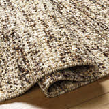 Close-up of the Tan Gopi Area Rug showing its textured weave in tan, taupe, and black jute and wool fibers. Fold