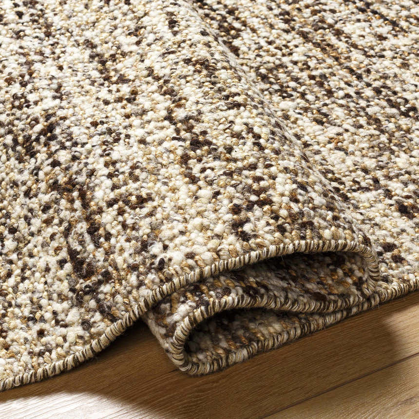Close-up of the Tan Gopi Area Rug showing its textured weave in tan, taupe, and black jute and wool fibers. Fold