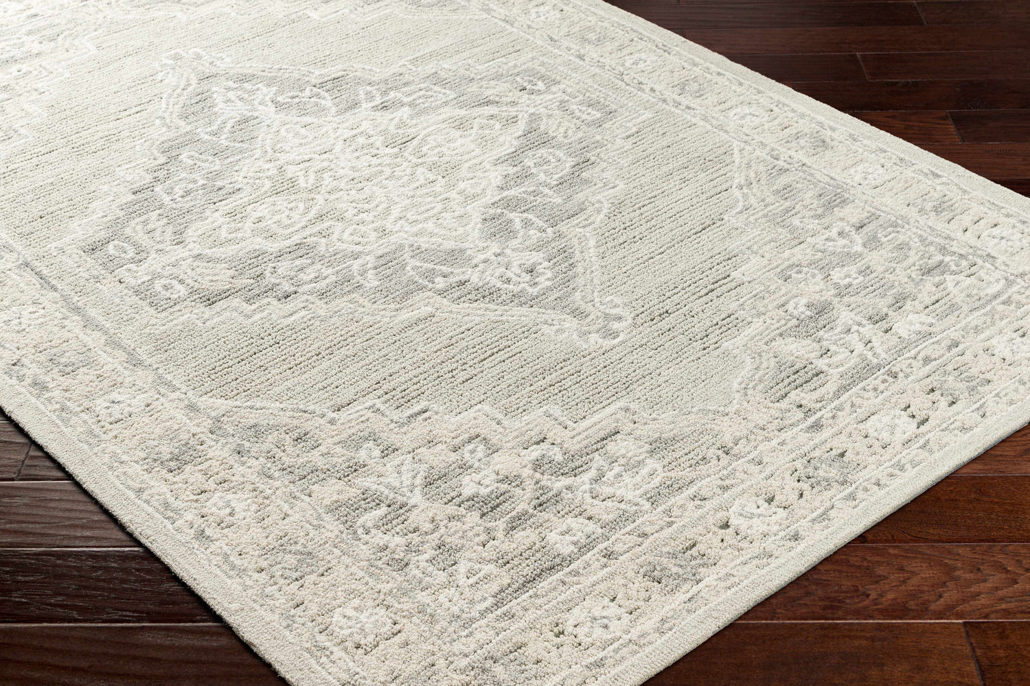 Close-up of the Nani Gray Wool Blend Area Rug showing its traditional gray and ivory floral pattern and hand-tufted texture. Corner