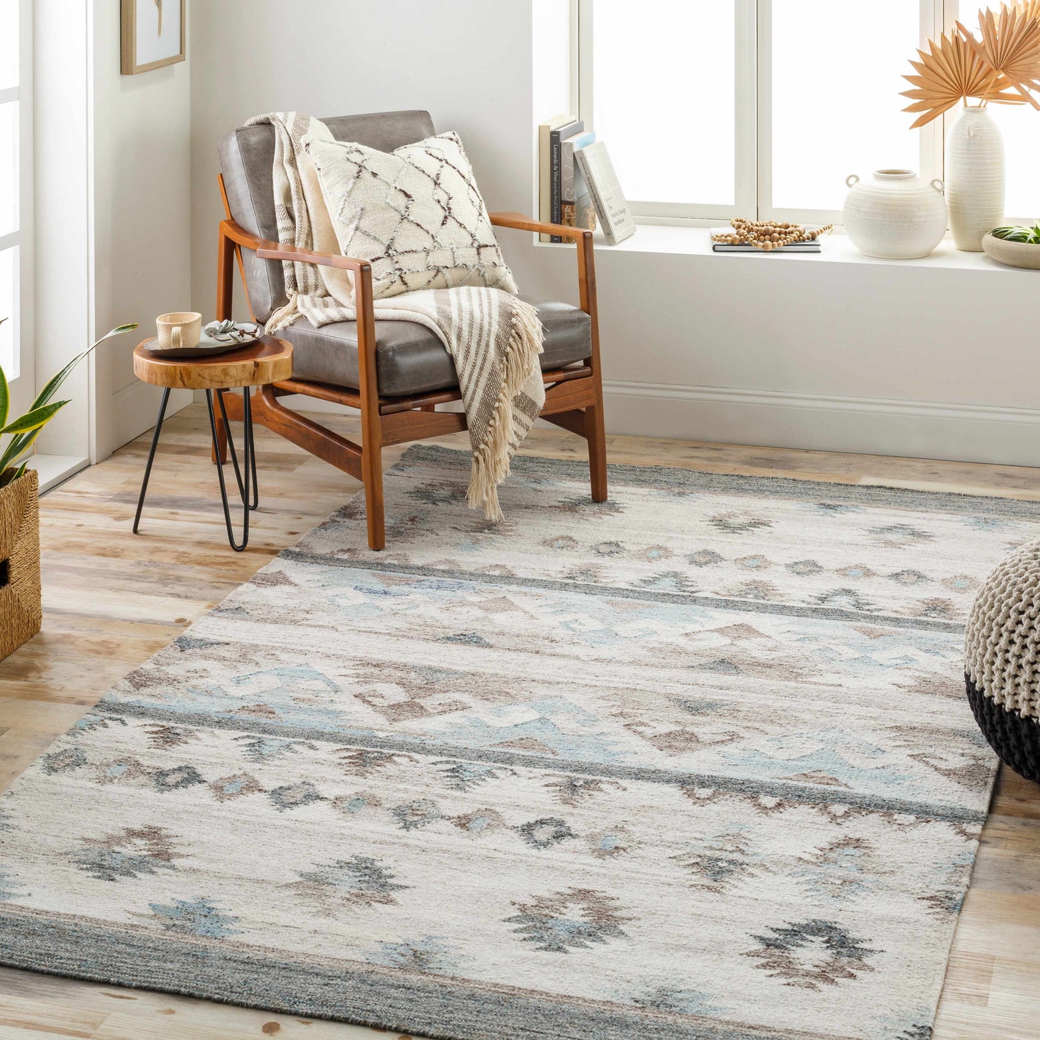 Living room scene with Duyen Area Rug in Scandinavian style. Features a gray chair, wood side table, and natural light. Roomscene-Rectangle