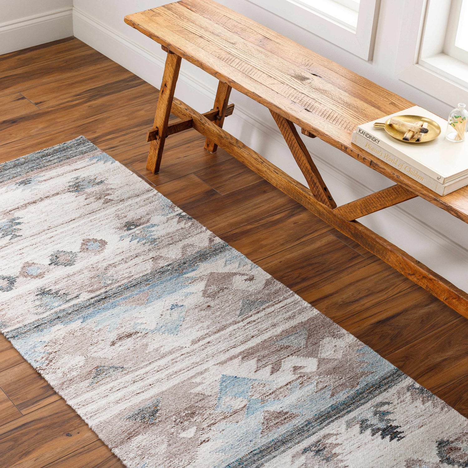 Hallway scene with Duyen Area Rug runner in blue, brown, and white. Rustic wood bench on hardwood floor. Roomscene-Runner