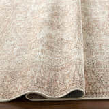 Close-up of the Margot Medallion Dusty Coral rug, a traditional design in beige, bone, and brown tones. Fold