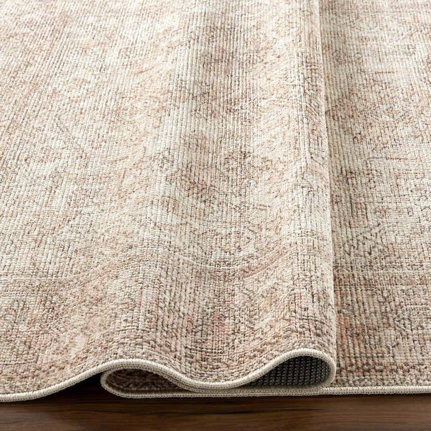 Close-up of the Margot Medallion Dusty Coral rug, a traditional design in beige, bone, and brown tones. Fold