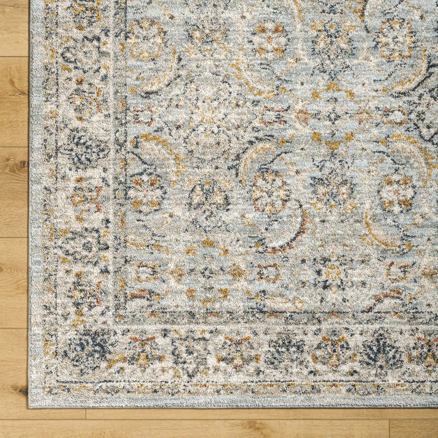 Close-up of the Jeven Blue Area Rug showing traditional beige and beachhouse blue floral pattern and soft polyester texture. Corner