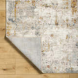 Close-up of Kacia Area Rug in beige and bone. Contemporary style with abstract pattern and visible rug backing. Fold