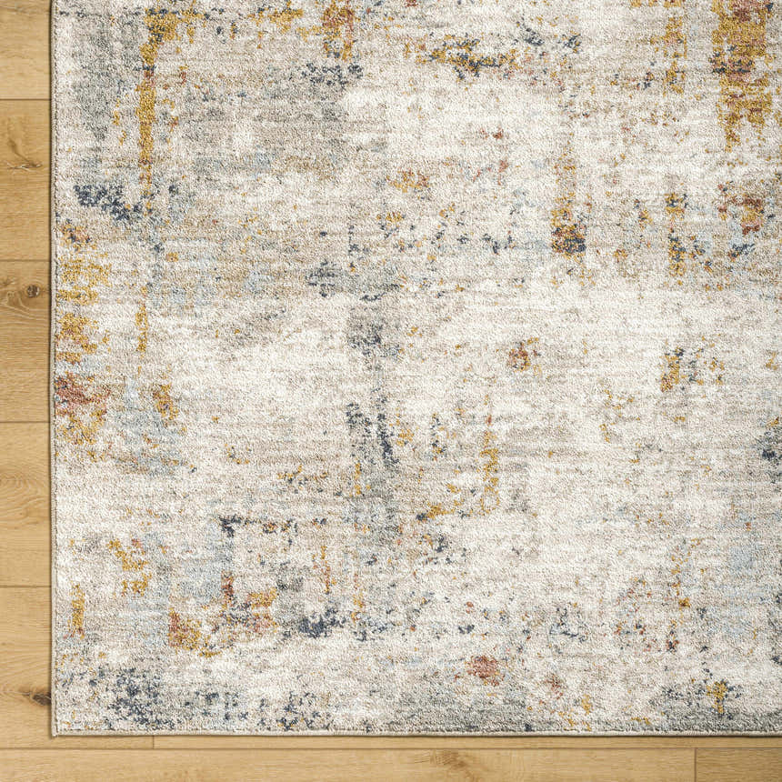 Close-up of the Kacia Area Rug showing beige, bone, gold, and blue abstract pattern and soft, textured weave. Corner