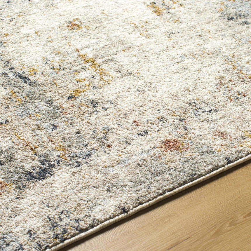 Close-up of the Kacia Area Rug showing beige, bone, gold, and navy abstract pattern and soft polyester texture. Texture