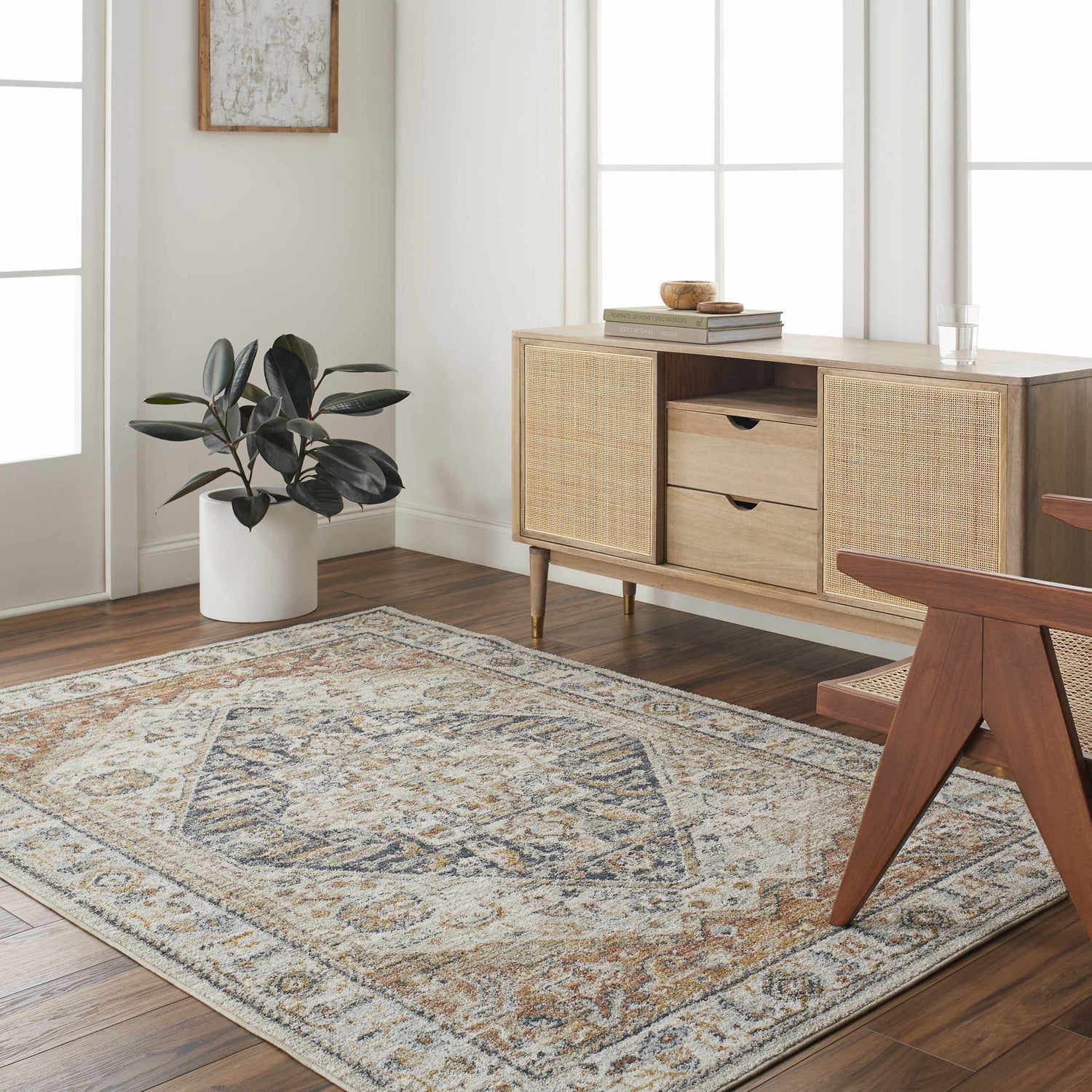 Living room scene with light gray Kuruk Area Rug, wood floors, and a rattan cabinet. Roomscene-Rectangle