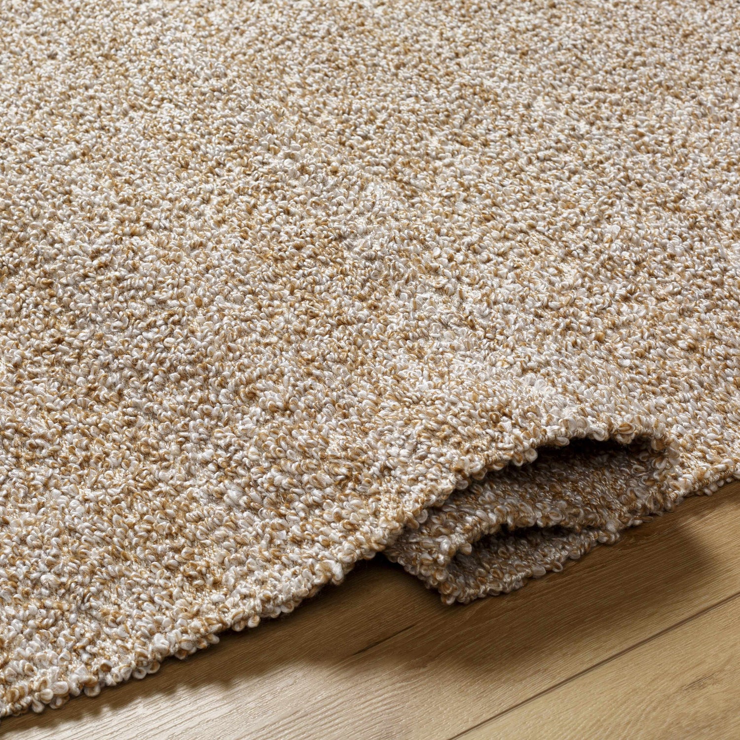 Close-up of the textured Kamil Beige Solid Area Rug, a lambswool and light brown hand woven rug. Fold