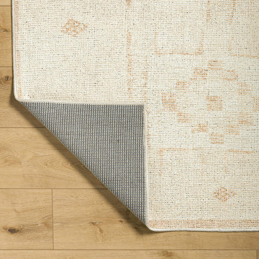 Close-up of Solana Medallion Peach rug by Livabliss x Becki Owens. Beige rug with peach medallion pattern and gray backing. Fold