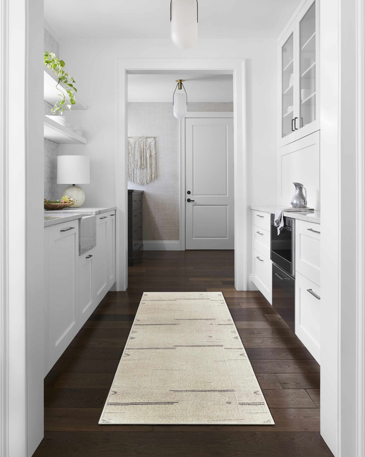 Beige Rivin Rug by Becki Owens x Livabliss in a bright, white kitchen hallway with dark wood floors. Roomscene-Runner