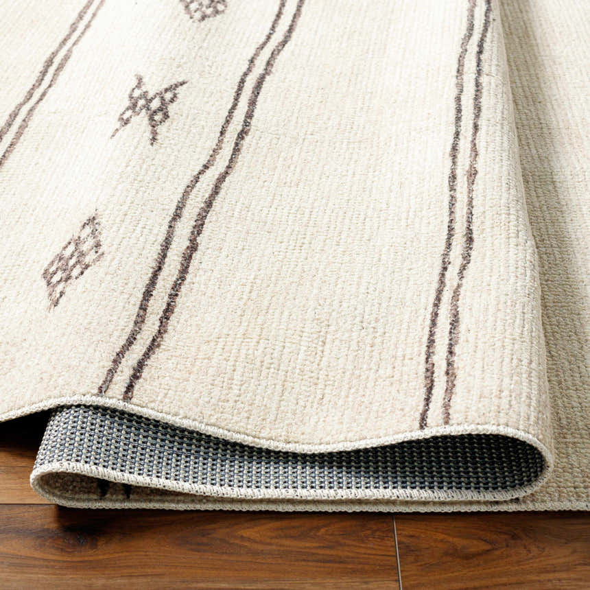 Close-up of the Rivi Moroccan Beige rug showing its beige color, brown stripes, and geometric pattern. Farmhouse style. Fold