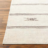 Close-up of the Rivi Moroccan Beige rug showing its textured beige pile and simple dark brown stripe pattern. Front