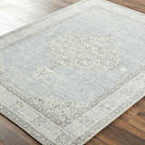 Close-up of Lila Medallion Denim Area Rug. Farmhouse style rug with charcoal, gray, and nutmeg medallion pattern. Corner