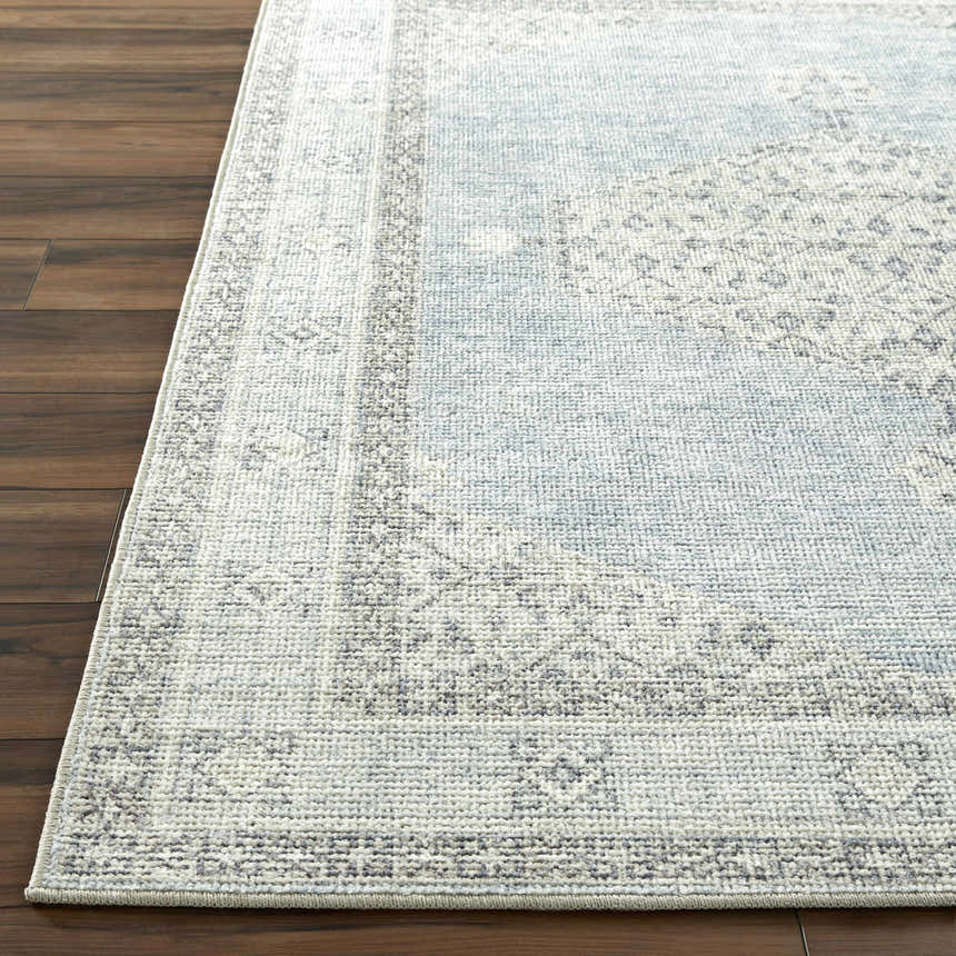 Close-up of the Lila Medallion Denim Area Rug. Farmhouse style rug in charcoal, gray, and denim on a dark wood floor. Front