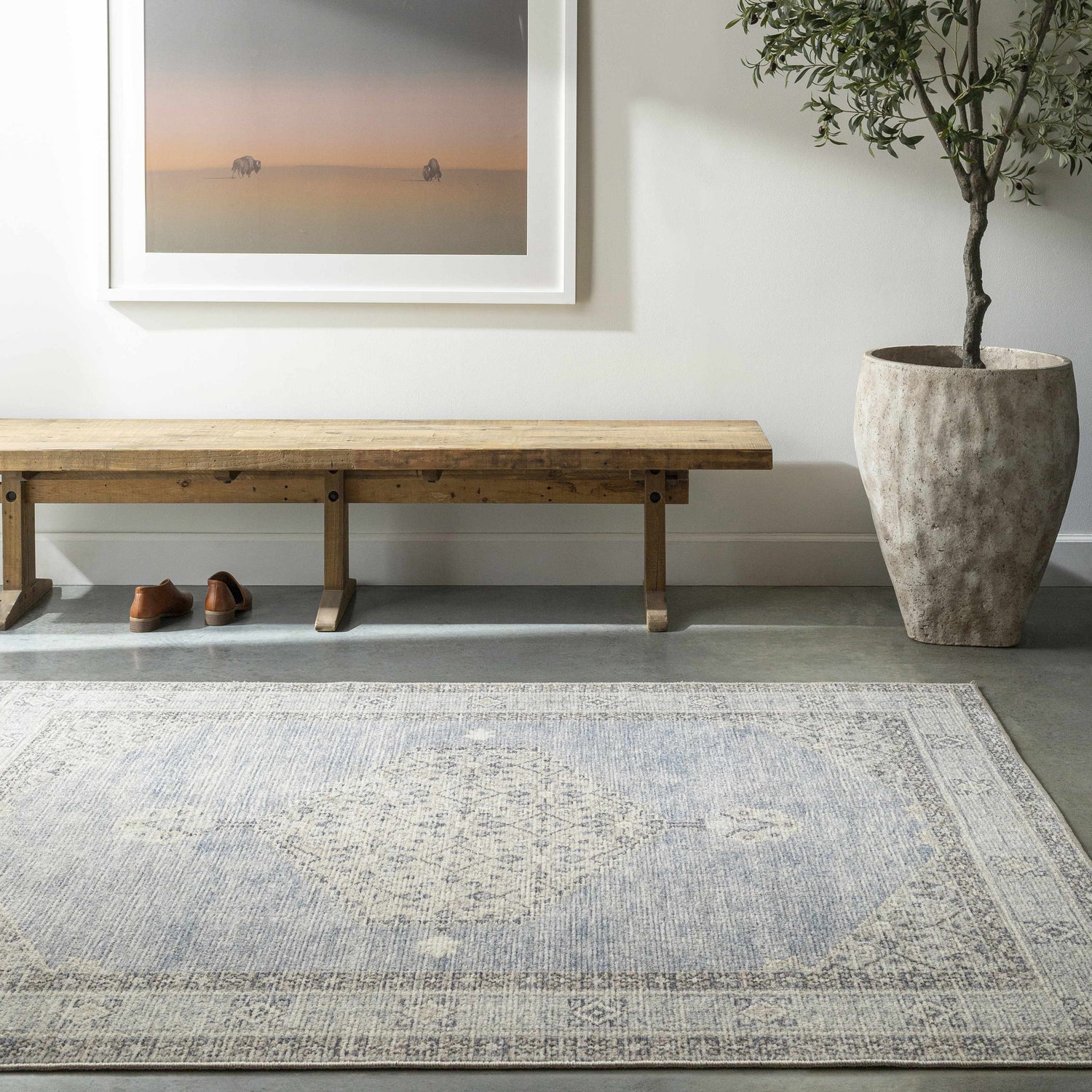 Entryway with wood bench, potted tree, and Lila Medallion Denim Area Rug in charcoal, dark gray, and light gray. Roomscene-Rectangle