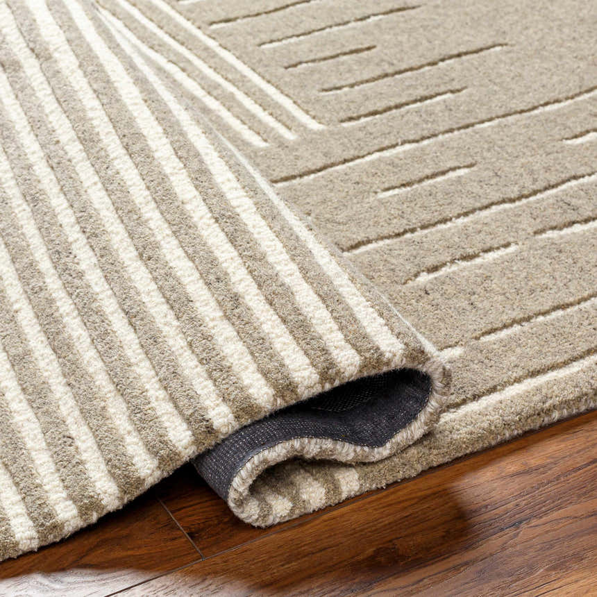 Close-up of the Akuji Area Rug showing its hand-tufted wool texture and geometric striped pattern in light peach and brown. Fold