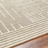 Close-up of the hand-tufted Akuji Area Rug. Features a contemporary geometric design in light peach and medium gray wool. Texture