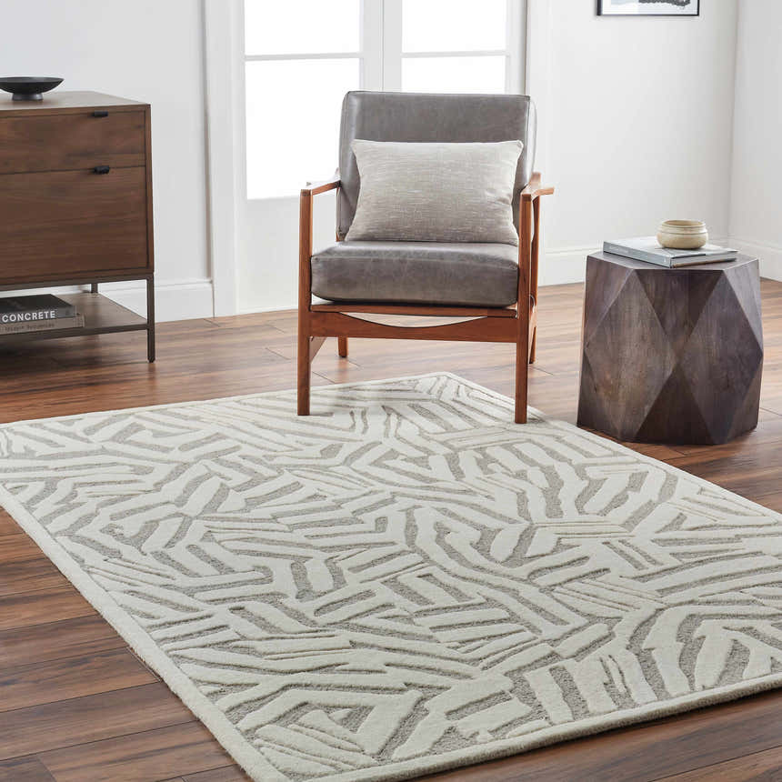 Living room scene with a gray chair and Avian Cream Wool Area Rug with a beige abstract pattern. Roomscene-Rectangle