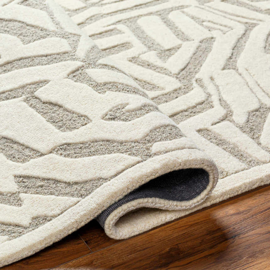 Close-up of the Avian Cream Wool Area Rug showing its beige, bone, and gray abstract pattern and hand-tufted texture. Fold