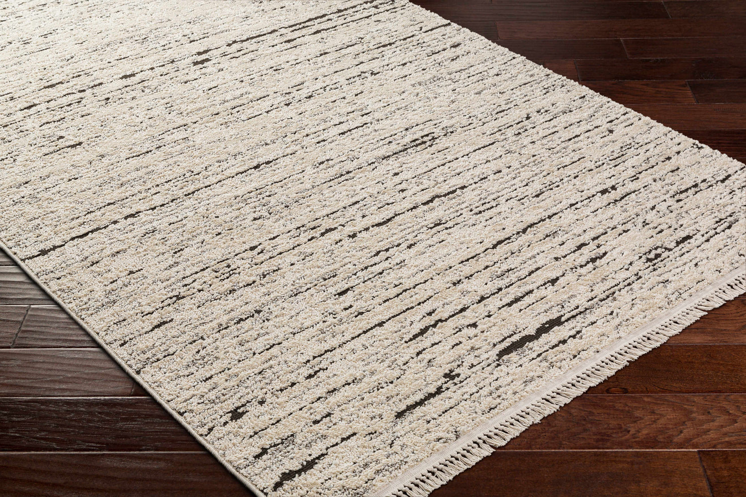 Close-up of the Elian Area Rug. Bone and dark brown abstract pattern on a textured, machine-woven pile. Corner