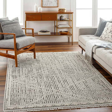 Living room scene with gray sofa and chair featuring the Luuk Area Rug in dark brown and ivory. Roomscene-Rectangle