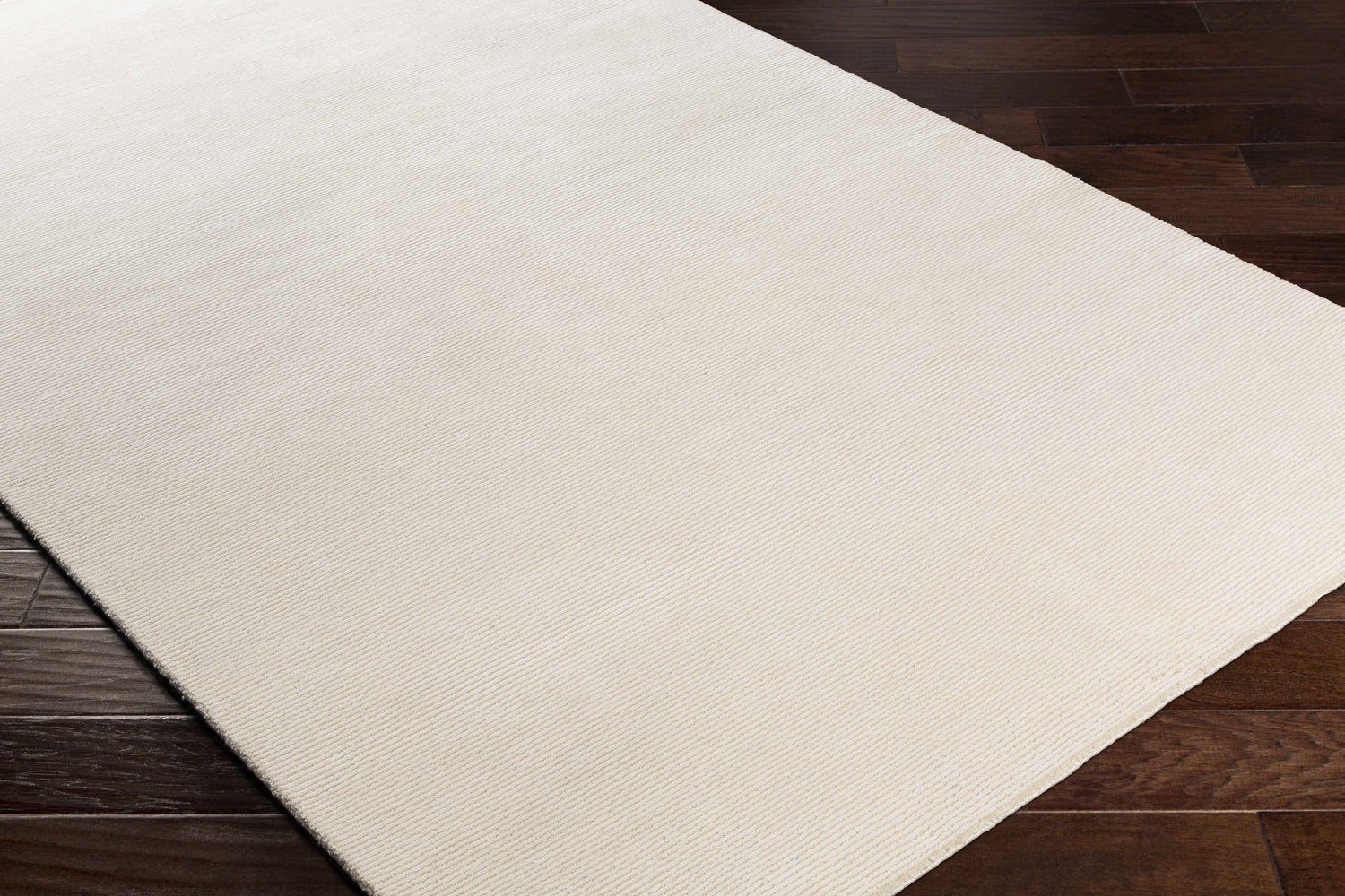 Close-up of the Sabinsville Carpet in cream, showing its subtle striped texture on dark wood flooring. Corner