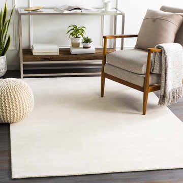 Neutral living room scene with a cream Sabinsville Carpet, wood chair, pouf, and console table. Roomscene-Rectangle