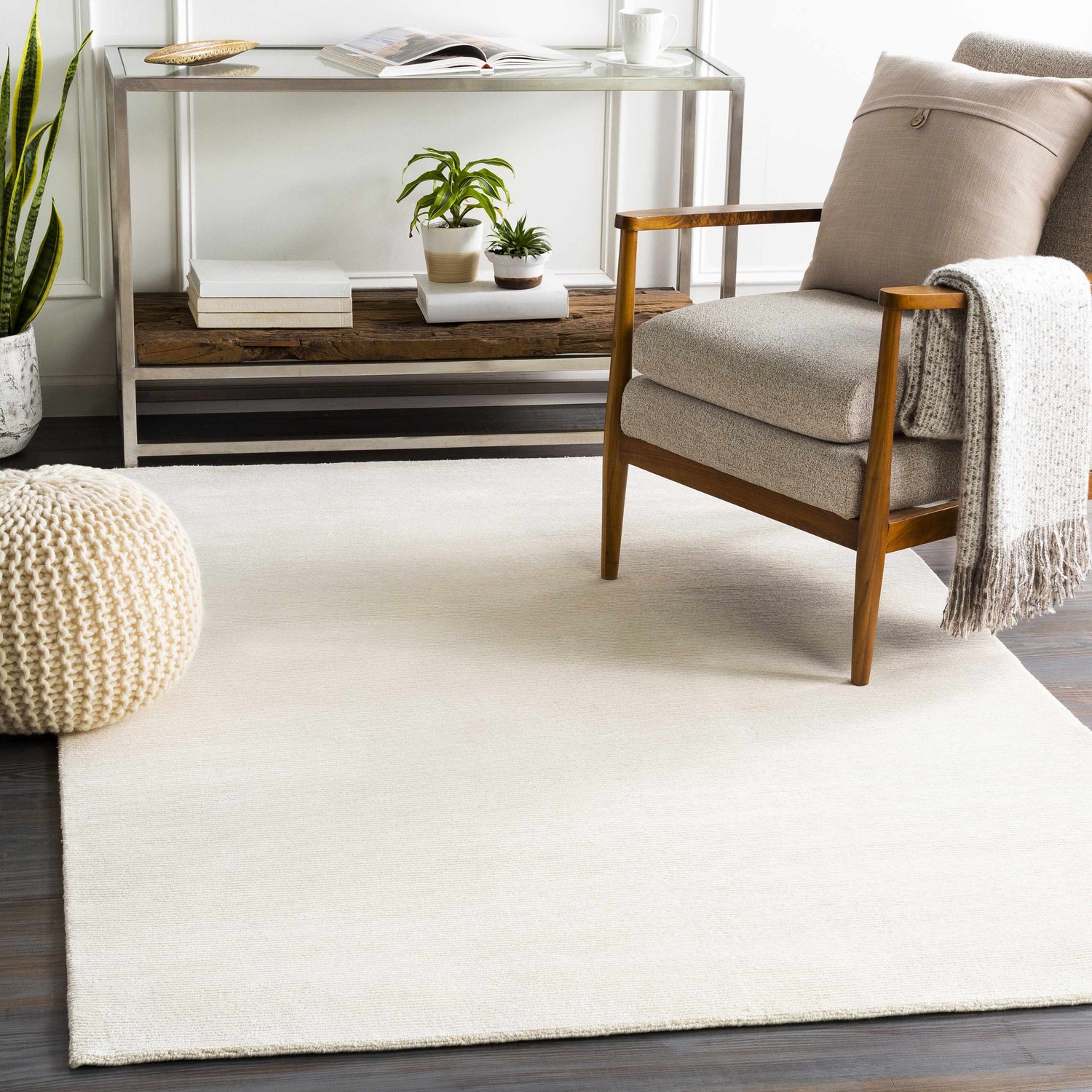 Neutral living room scene with a cream Sabinsville Carpet, wood chair, pouf, and console table. Roomscene-Rectangle