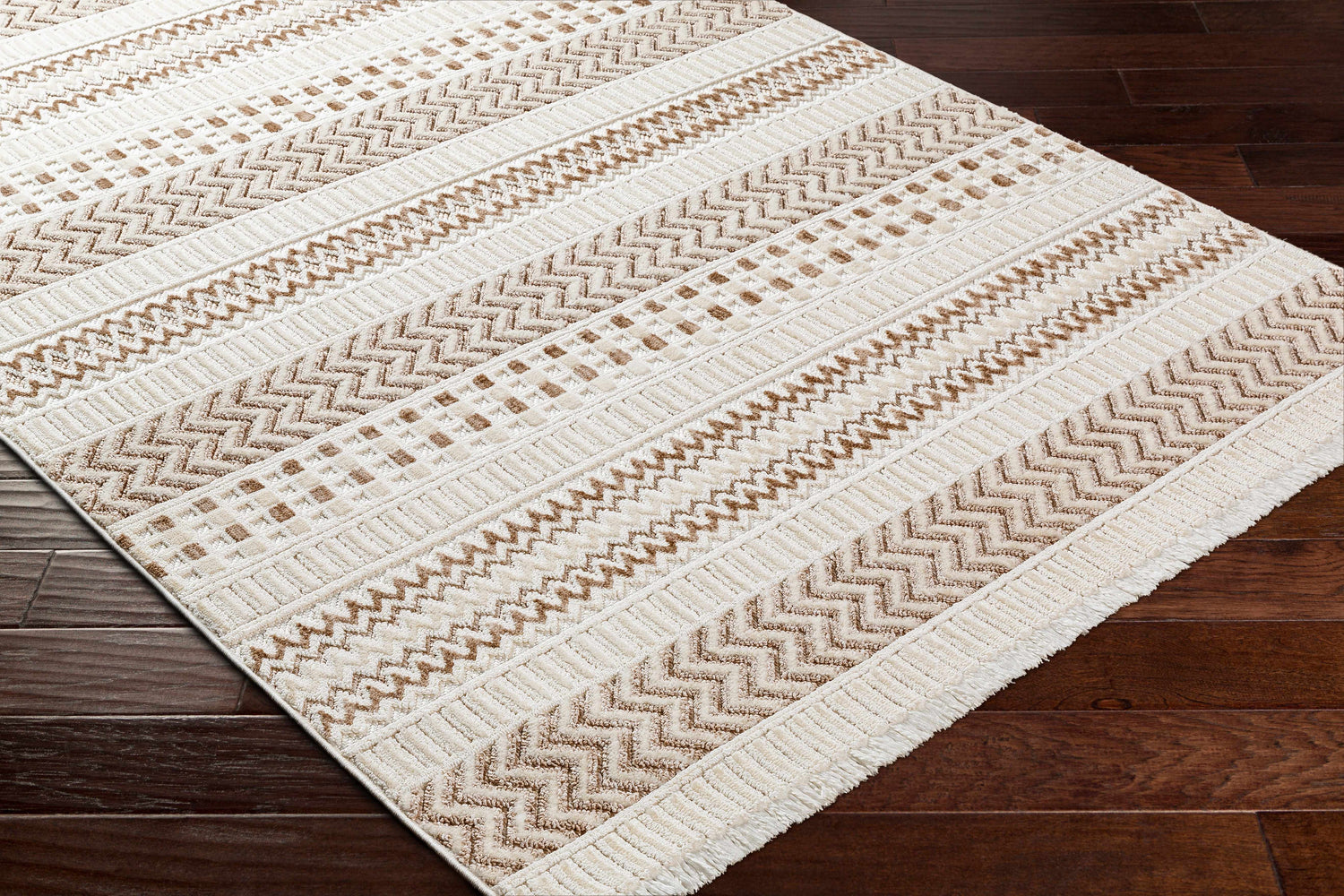 Close-up of Eiko Beige Textured Saxony Rug with Fringes, showing geometric patterns in bone, driftwood, and nutmeg colors. Corner